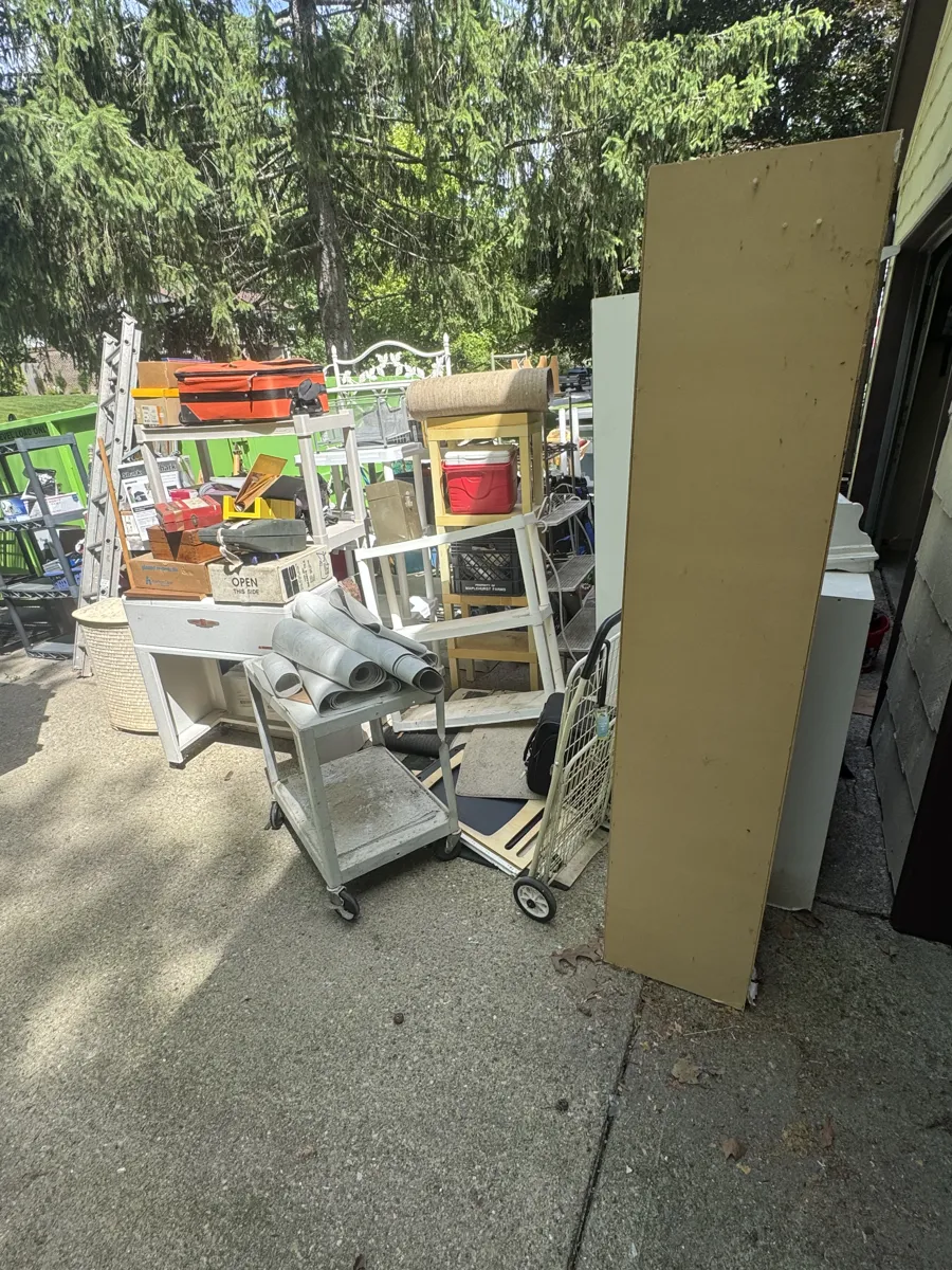 Junk pile staged at a driveway curb for pickup