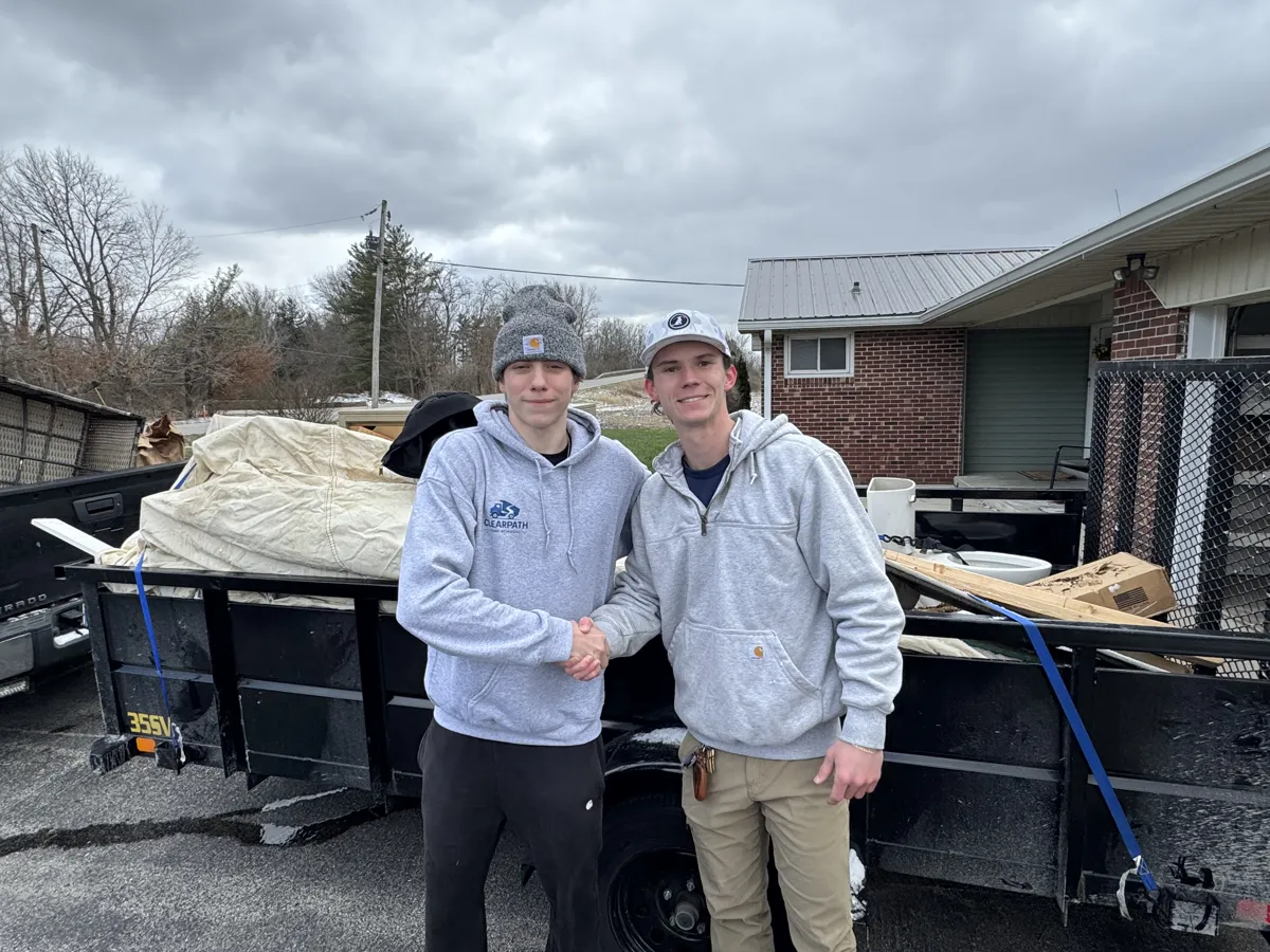 ClearPath Junk Removal crew shaking hands next to a loaded trailer after a job
